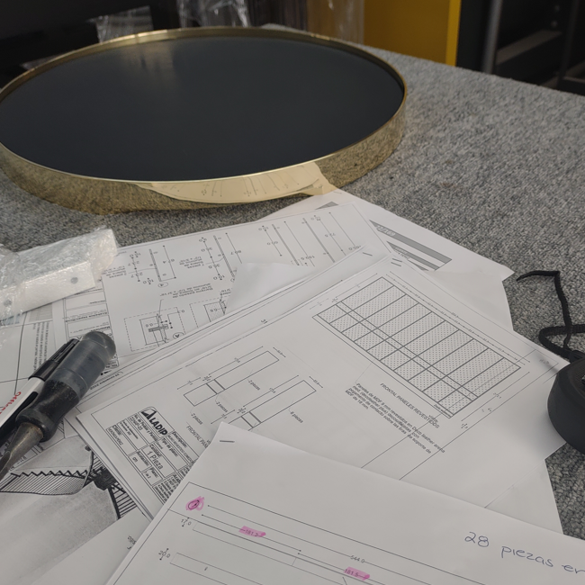 Una mesa con planos y una pieza redonda de latón
